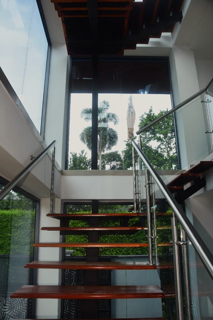 Escalera contemporánea con barandas de vidrio y acabados en madera